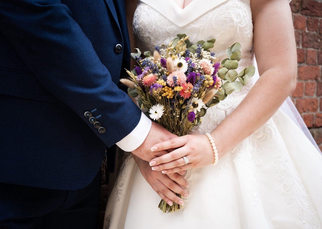 Bride and bridegroom holding a dried flower bouquet
