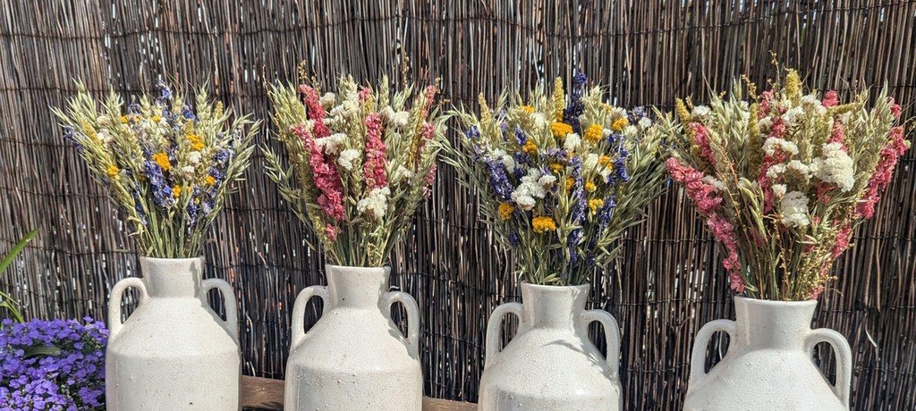 4 Jugs containing yellow, pink, purple and white dried flower arrangements