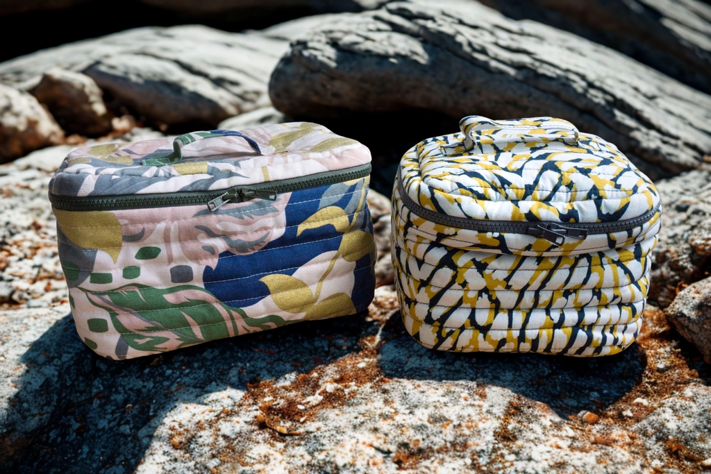 Deux trousses de toilettes vanity posé dans une salle de bain en bois.