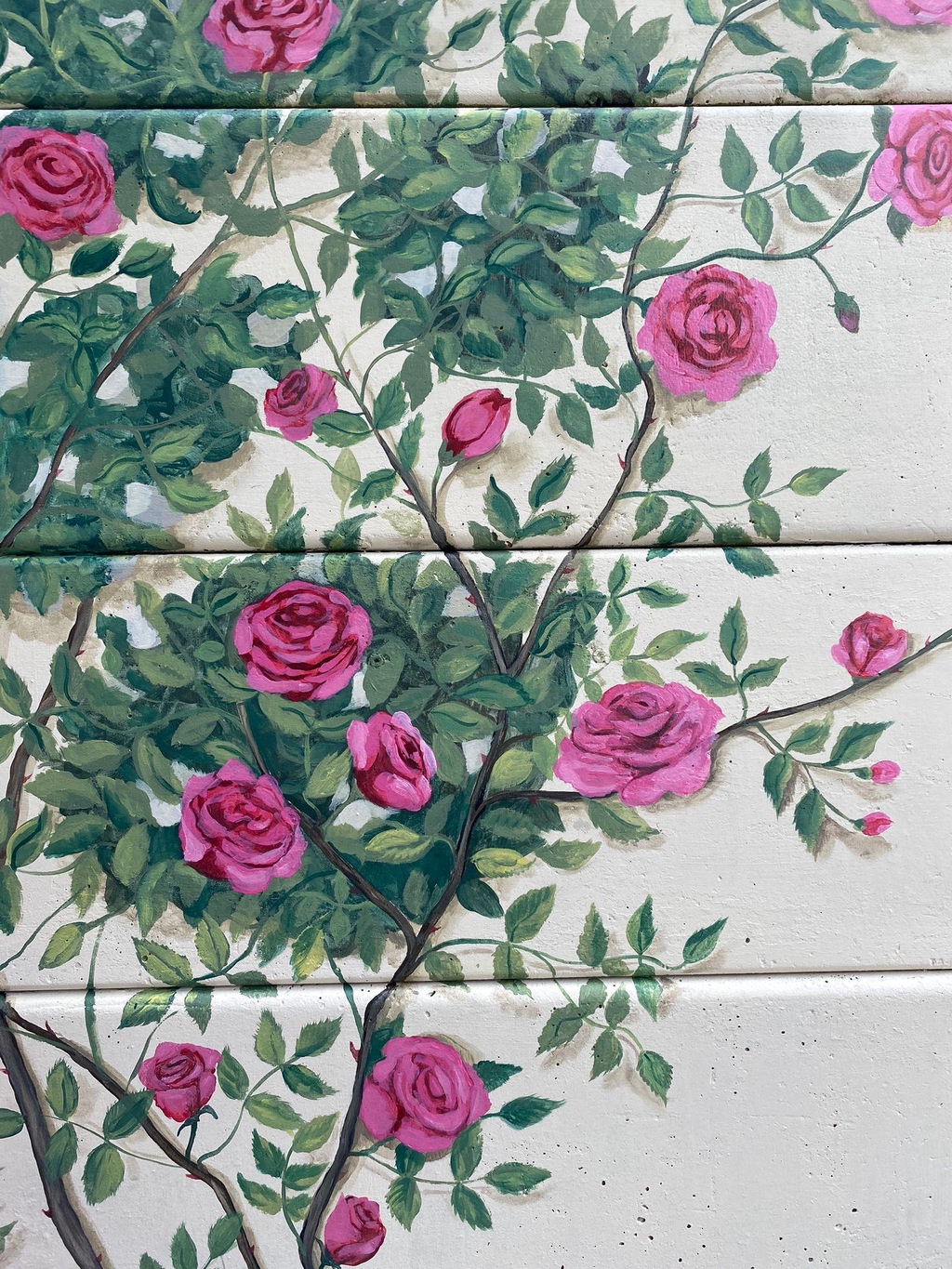 handprinted roses on a garden fence outside mural