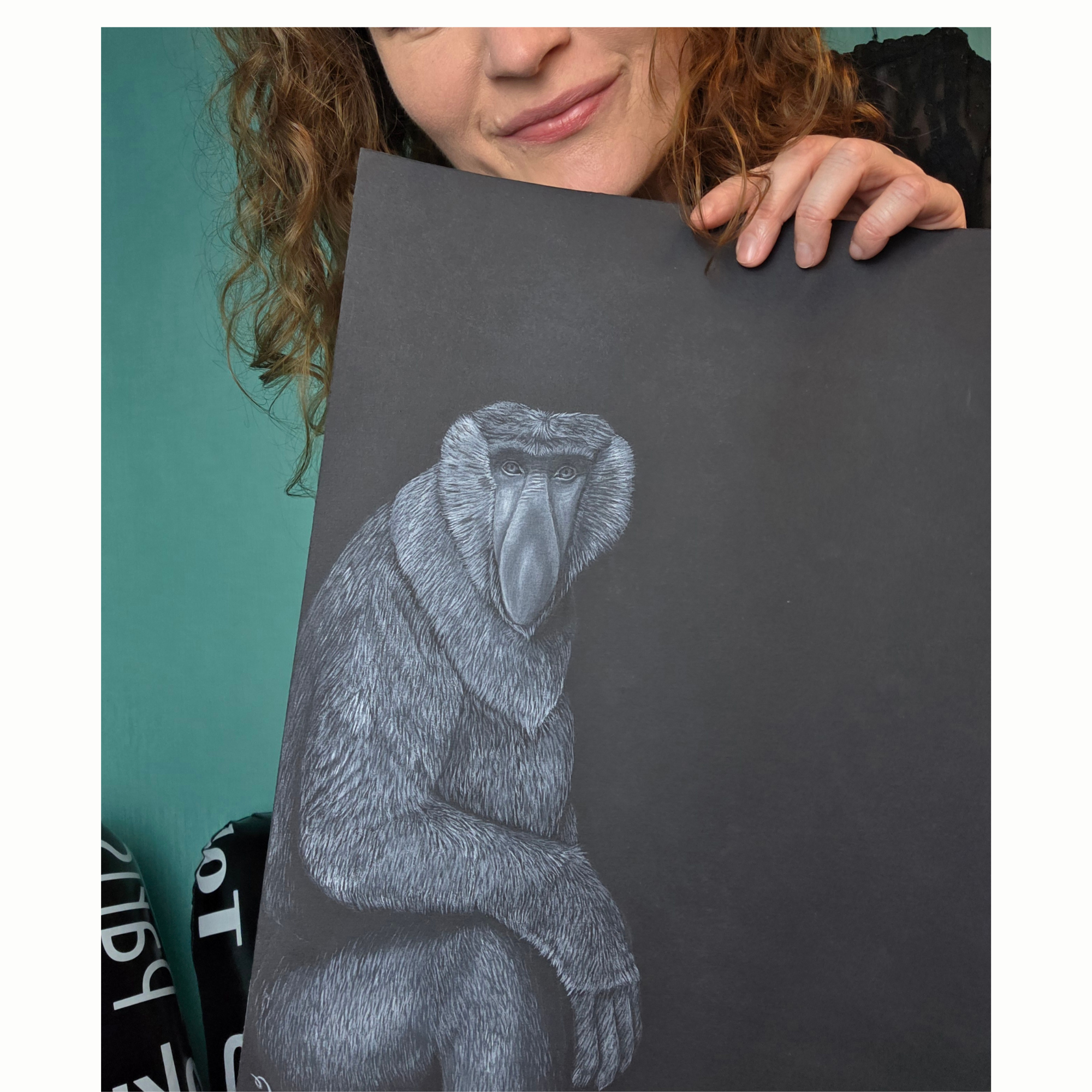 L'artiste peintre Cécilia PELISSIER présentant une aquarelle originale d'animal en danger sur papier noir ( ici un Nasique) format de collection