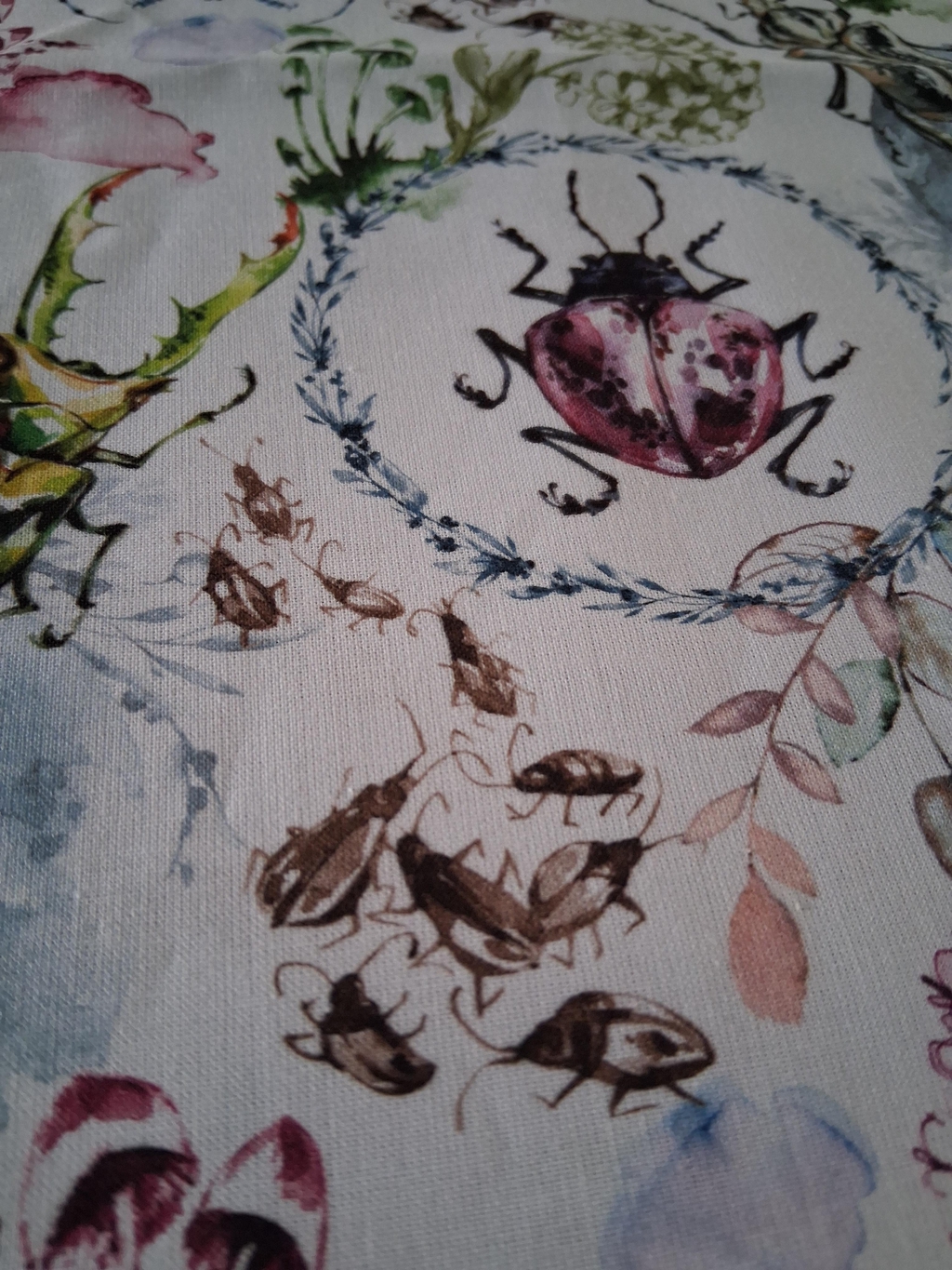 Tissu représentant des insectes et des feuillages réalisés à l'aquarelle dans des tons doux. 