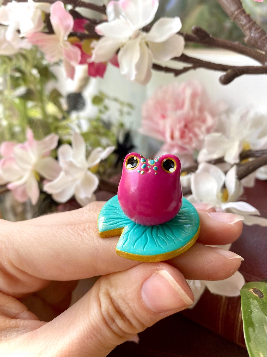 Bannière présentant une petite grenouillet rose sculptée reposant sur un nénuphar. Une figurine décorative ideéale pour apporter une touche de magie et de douceur à son intérieur. 