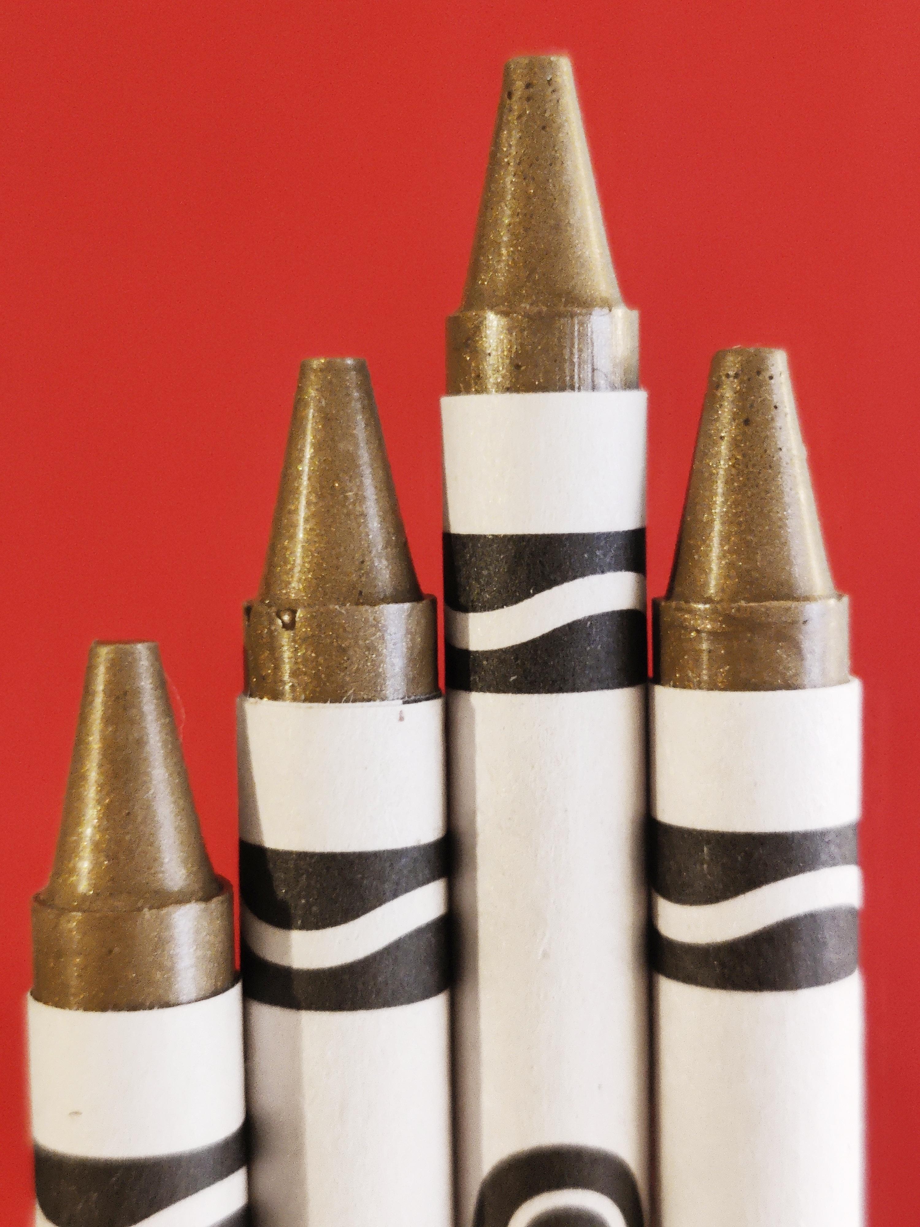quatre crayons en cire de couleur dorée sur un fond rouge