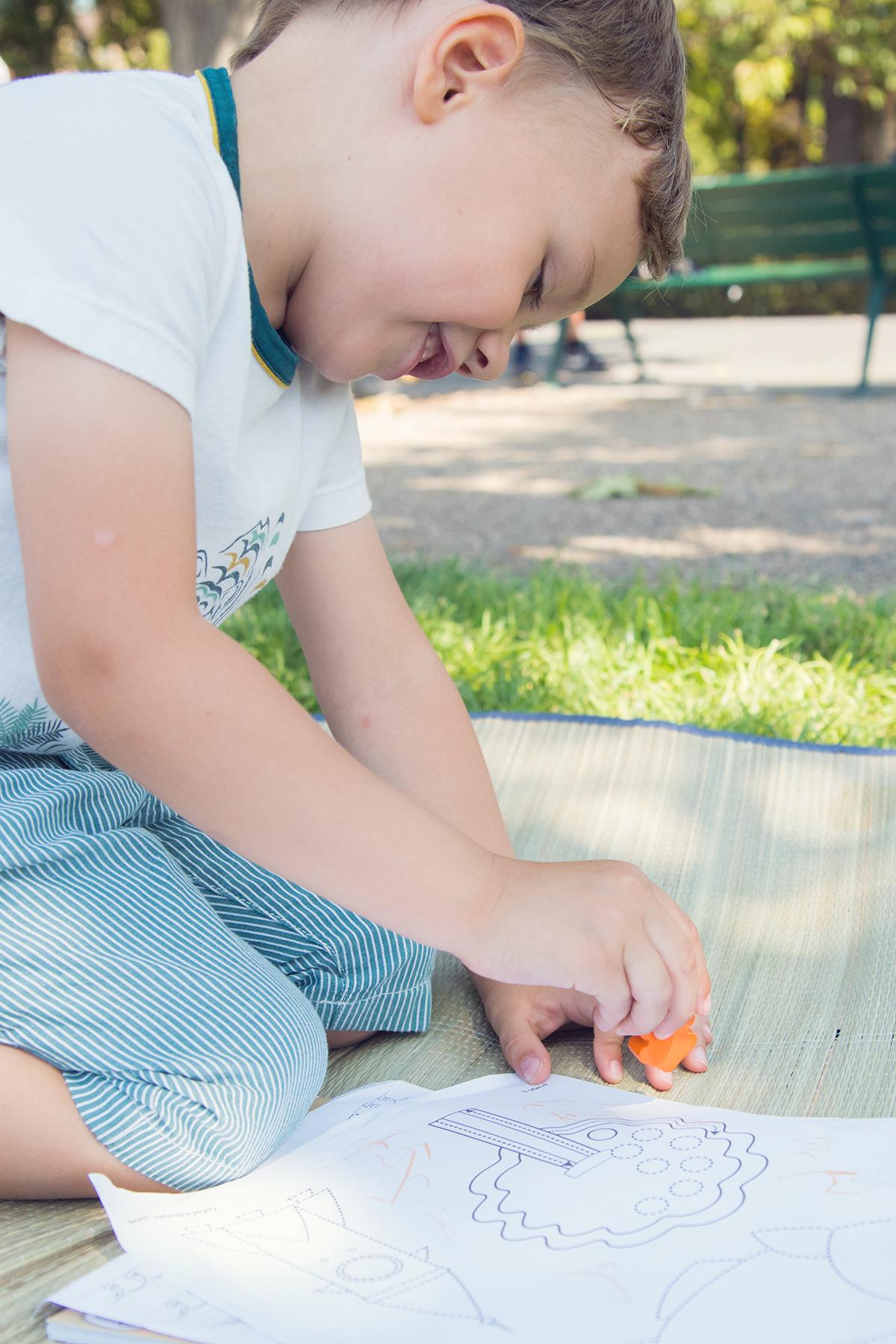 enfant fait du coloriage dans un parc