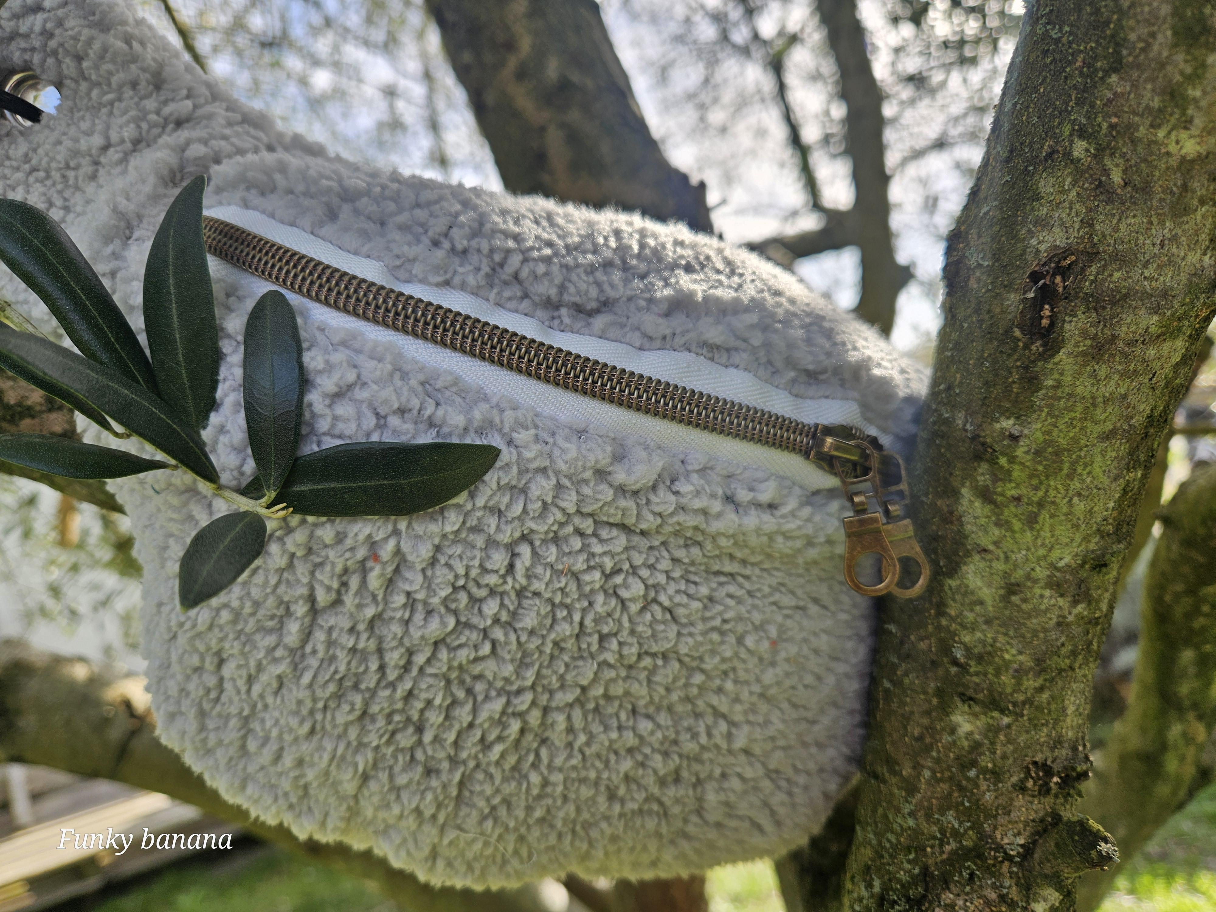 Sac banane de forme classique en sherpa moumoute couleur crème. Décor végétal, soleil présent