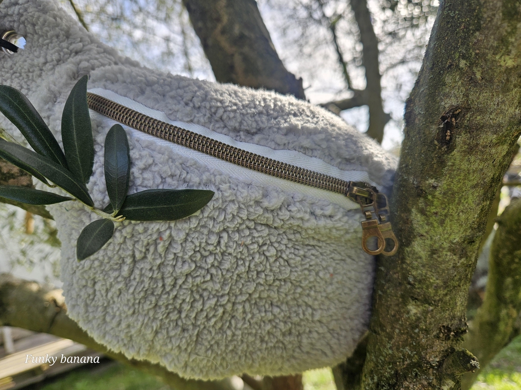 Sac banane de forme classique en sherpa moumoute couleur crème. Décor végétal, soleil présent 