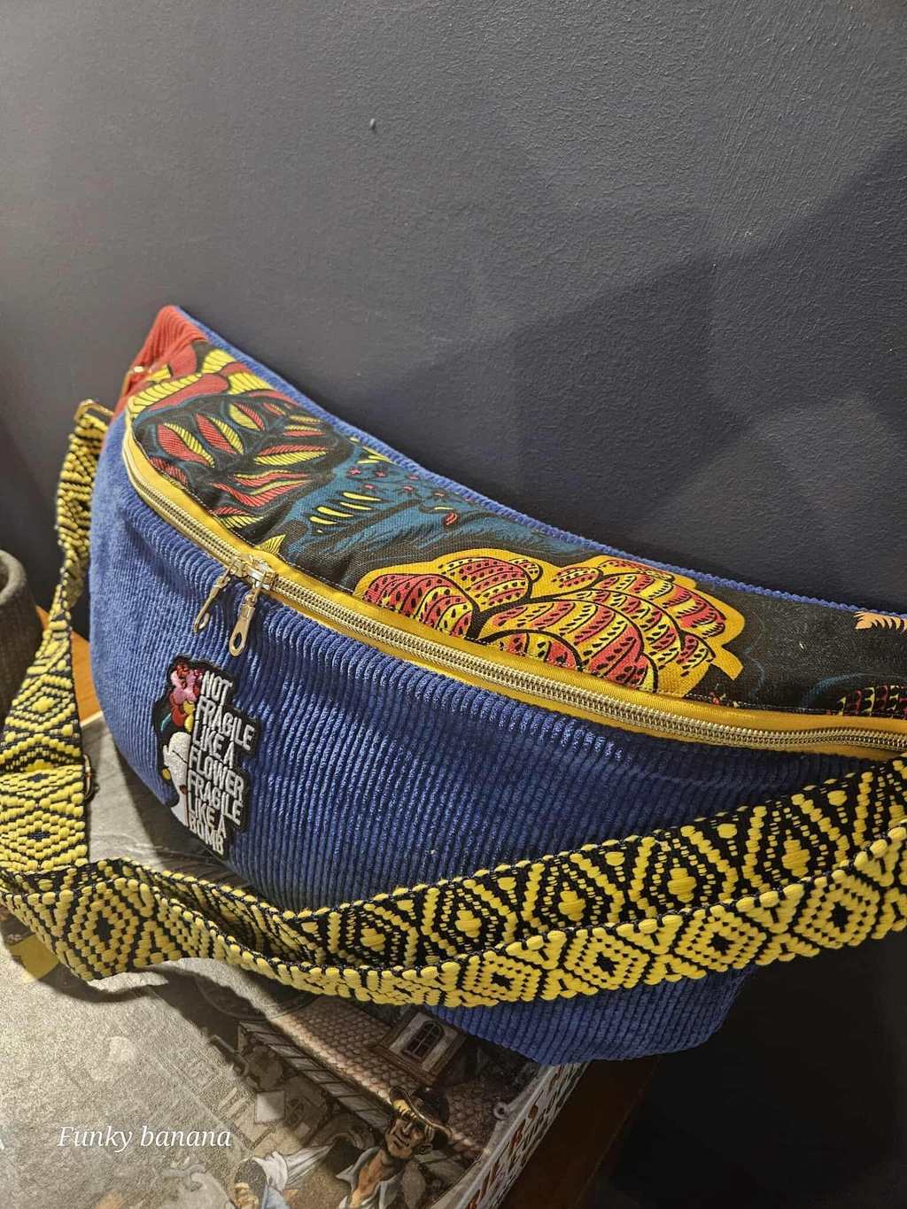 Sac banane sur mesure multi matières pour Gaëlle funky banana forme nomade XL velours côtelé bleu, zip jaune, imprimé Pondichéry, écusson Frida Kahlo, sangle bleue et jaune 