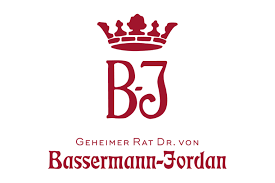 Die Geschichte des Weinguts Bassermann-Jordan ist die Geschichte einer Familiendynastie, die den Qualitätsweinbau mit begründet hat und seit knapp 300 Jahren maßgeblich beeinflusst. In Generationen wurde das Pfälzer Weingut aufgebaut, das heute zur Weltspitze zählt.
Die Weinberge in Forst, Deidesheim und Ruppertsberg umfassen ca. 49 ha Rebfläche in 20 Einzellagen. Davon sind mehr als ein Drittel Spitzenlagen wie Hohenmorgen, Kirchenstück und Jesuitengarten. Mit Pionier- und Forschergeist wurden die Weinberge von Anfang an mit innovativen Anbaumethoden bewirtschaftet, um einerseits die Qualität zu steigern und andererseits auch ein Stück Pfälzer Weinbaukultur zu bewahren. Dazu gehört u. a. auch die Hinwendung zu biologischen Anbaumethoden wie ein vorbeugender Pflanzenschutz durch natürliche Präparate und sehr viel Handarbeit. Dadurch kann sich eine artenreiche Flora und Fauna entfalten, die einen naturnahen und nachhaltigen Weinbau unterstützt.
Außerdem steht der behutsame Umgang mit den Trauben und die gezielte Selektion des Leseguts von Hand immer im Vordergrund. Das Ergebnis sind individuelle und charakterstarke Weine.
Der historische Weinkeller in Deidesheim steht heute vornehmlich für den traditionellen Ausbau der Weine im Holzfass. Behutsam reifen die Weine im jahrhundertelang gewachsenen Sandsteingewölbe. Hier entstehen auch die Sekte in traditioneller Flaschengärung.
Die moderne Kelter- und Kellerbetriebsstätte bietet darüber hinaus die Möglichkeit der Weinbereitung auf höchstem technischem Niveau und steht primär für den modernen, fruchtbetonten Ausbau. Dabei wird grundsätzlich viel Wert auf eine behutsame und natürliche Gärung ohne künstliche Zusatzstoffe gelegt.
Die unterschiedlichen Produktionsarten ermöglichen eine breite und nuancenreiche Stilistik. Auf der einen Seite entstehen terroirbetonte, mineralische Weine, die nachhaltig und lagerfähig im klassischen Stil des Weinguts sind. Auf der anderen werden feinfruchtige, belebte und hocharomatische Weine erzeugt – modern und expressiv.
