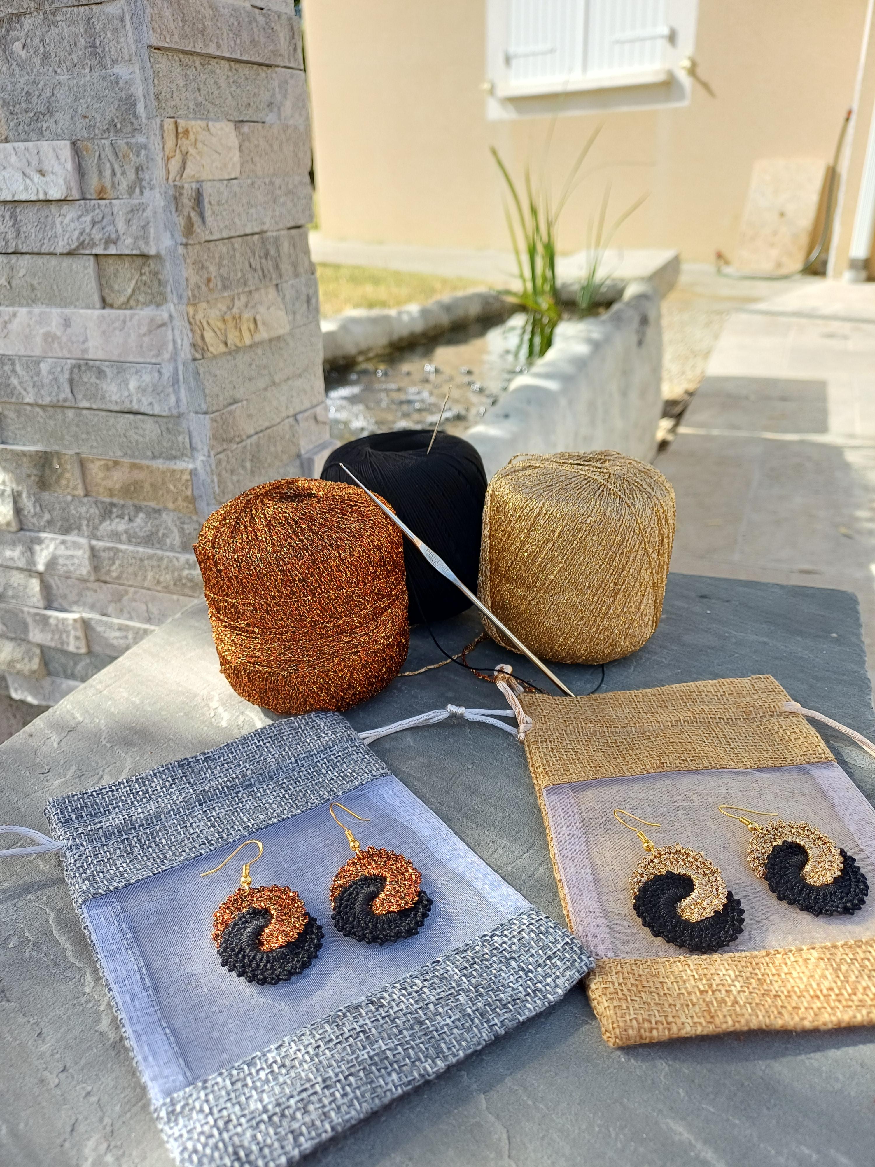 Pelotes de fil or et bronze et deux paires de boucles d oreilles or, bronze noir devant fontaine