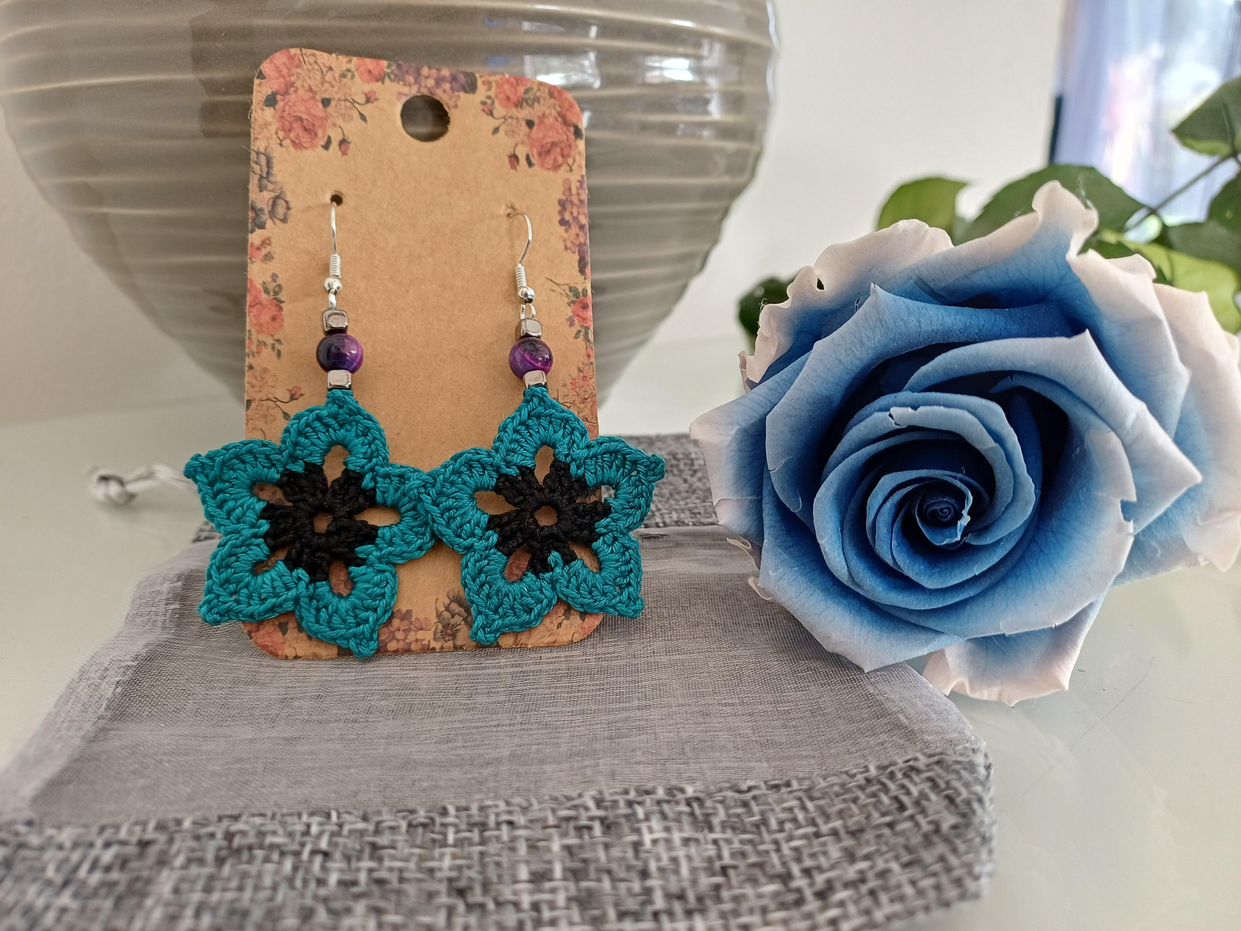 Boucles d'oreilles bleues en crochet avec petite en oeil de tigre bleue à coté d'une rose bleue