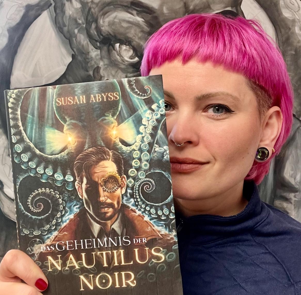 Susan Abyss hält ihr Buch „Das Geheimnis der Nautilus Noir“ in die Kamera 