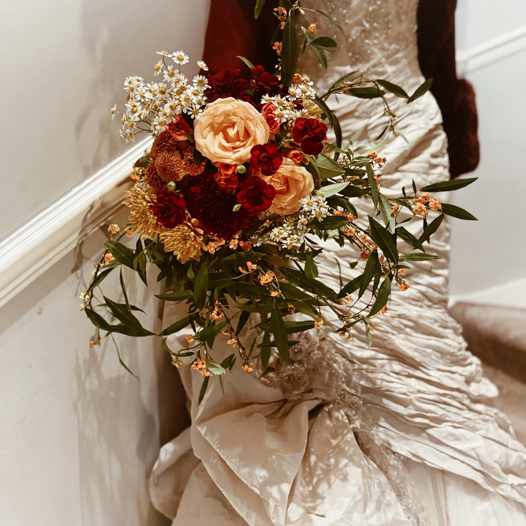 A bride with a bouquet in burgundy and golds
