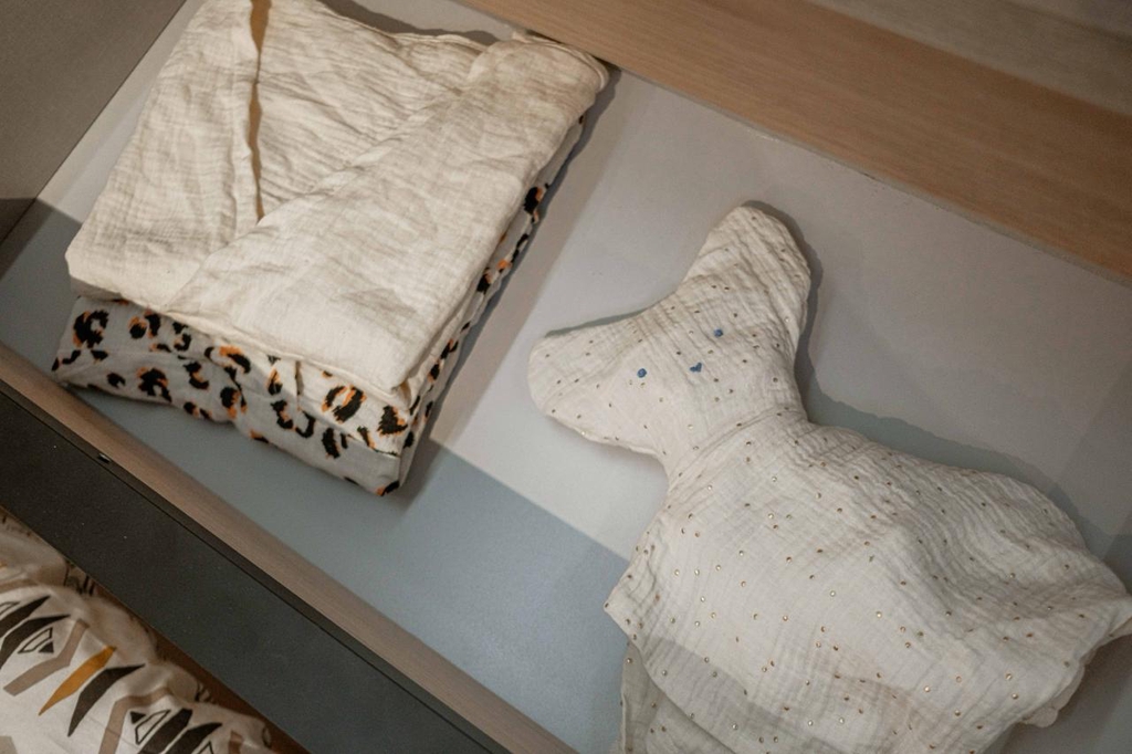 Deux pyjamas sont pliés sous forme de haut, un autre est replié sous forme de doudou. 