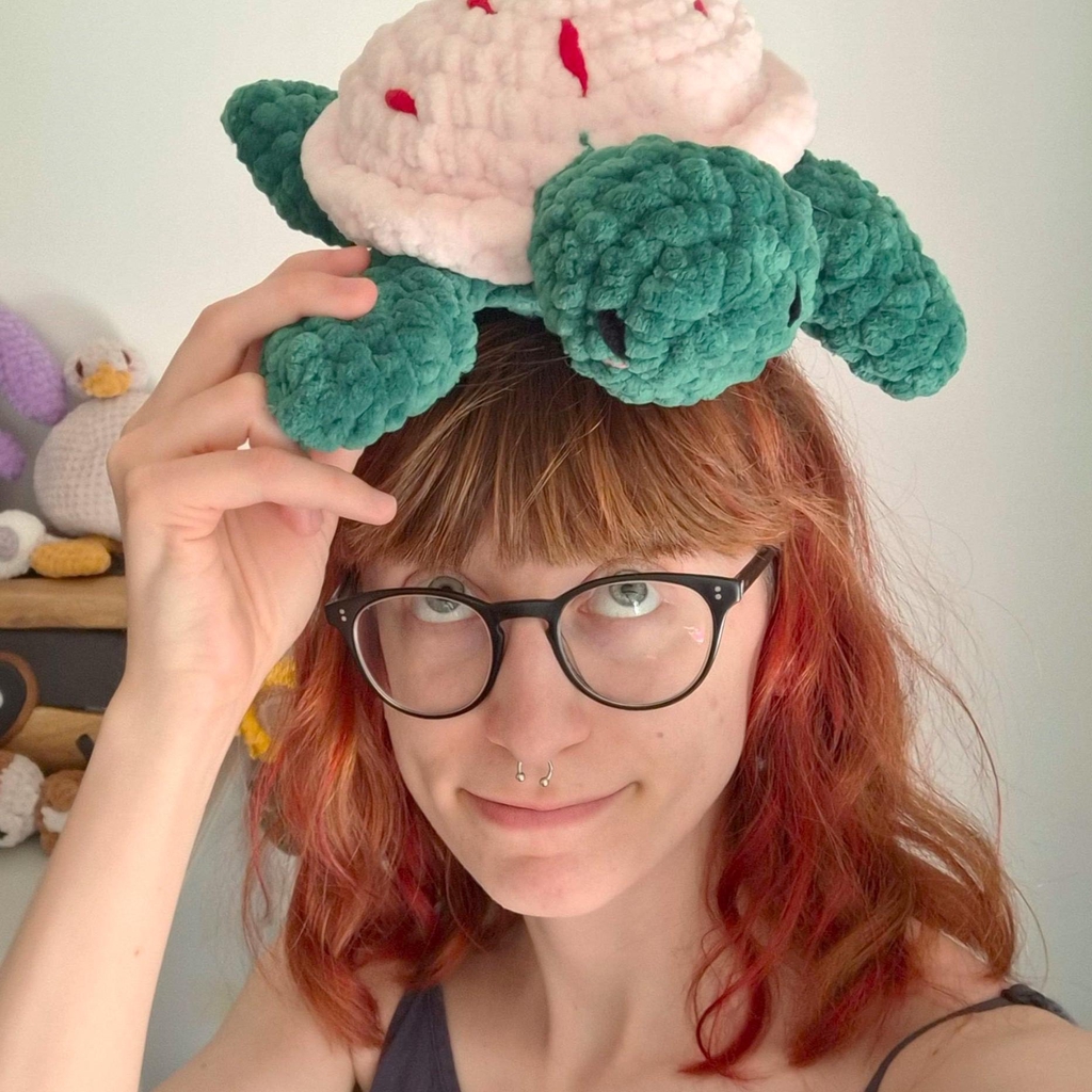 Image d'illustration Héliana, je me suis prise en photo de face, je tiens une peluche tortue au crochet pour la poser sur ma tête et je la regarde