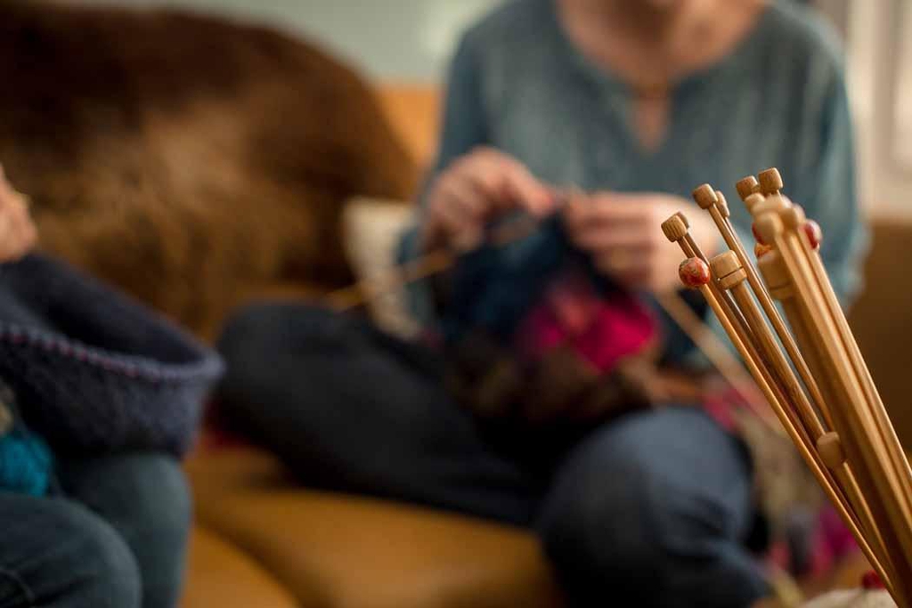 Adults sitting on a couch crafting together.