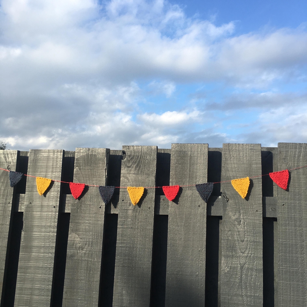 Knitted bunting hanging on a fence