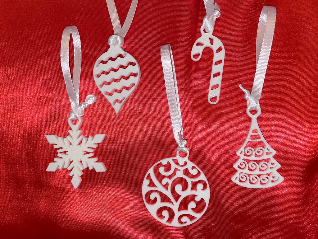 Five small white hanging Christmas decorations, shown on a red background