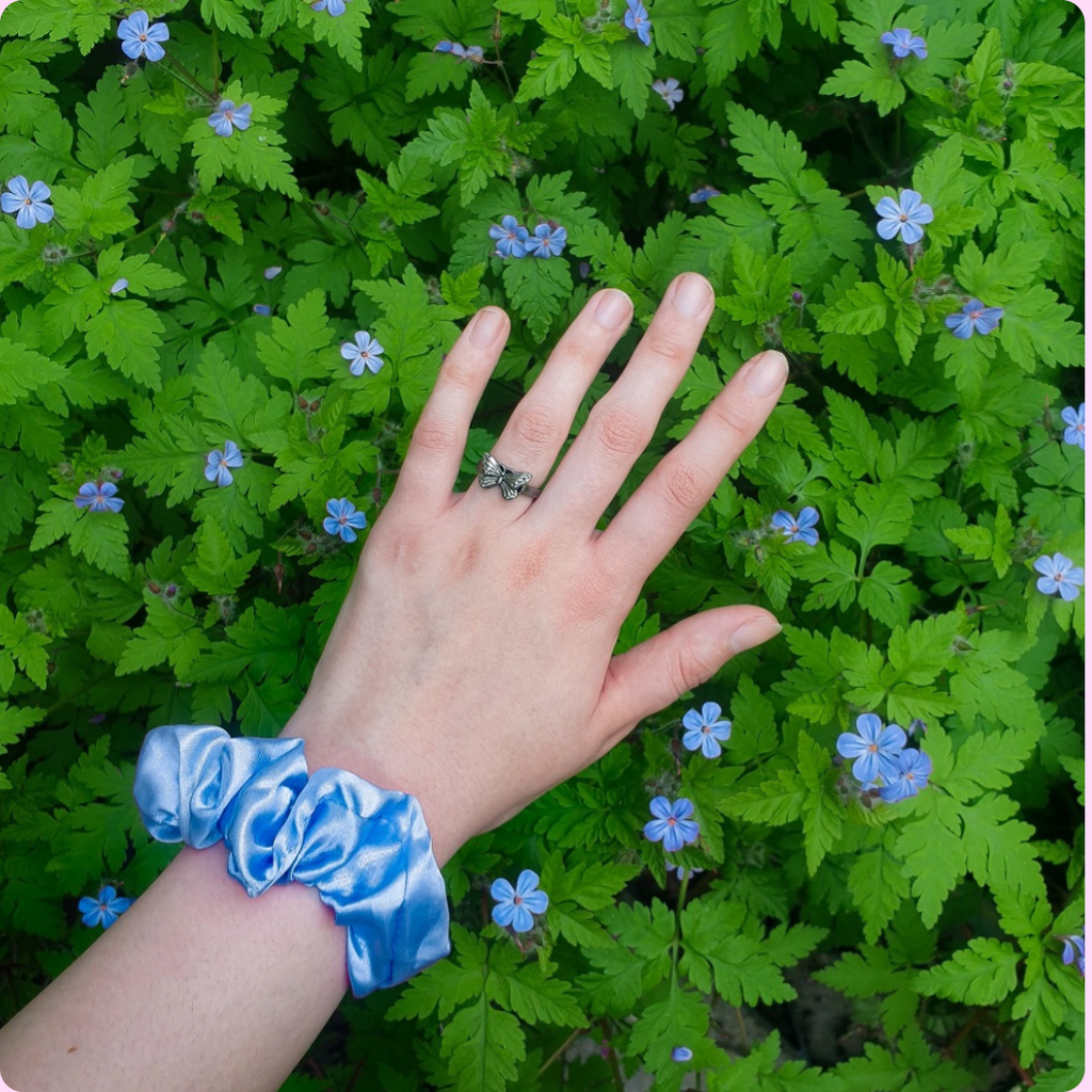 Blue scrunchie in front of some blue flowers