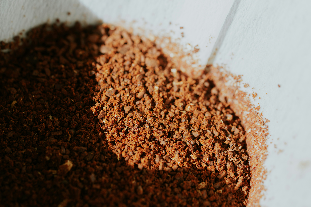 Coffee grounds sitting on filter paper in a pour over dripper