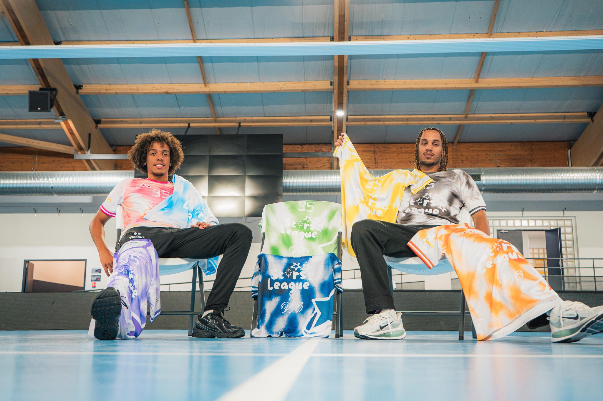 Deux joueurs assis dans un gymnase, vêtus des maillots tie-dye Stars League × VVØ
