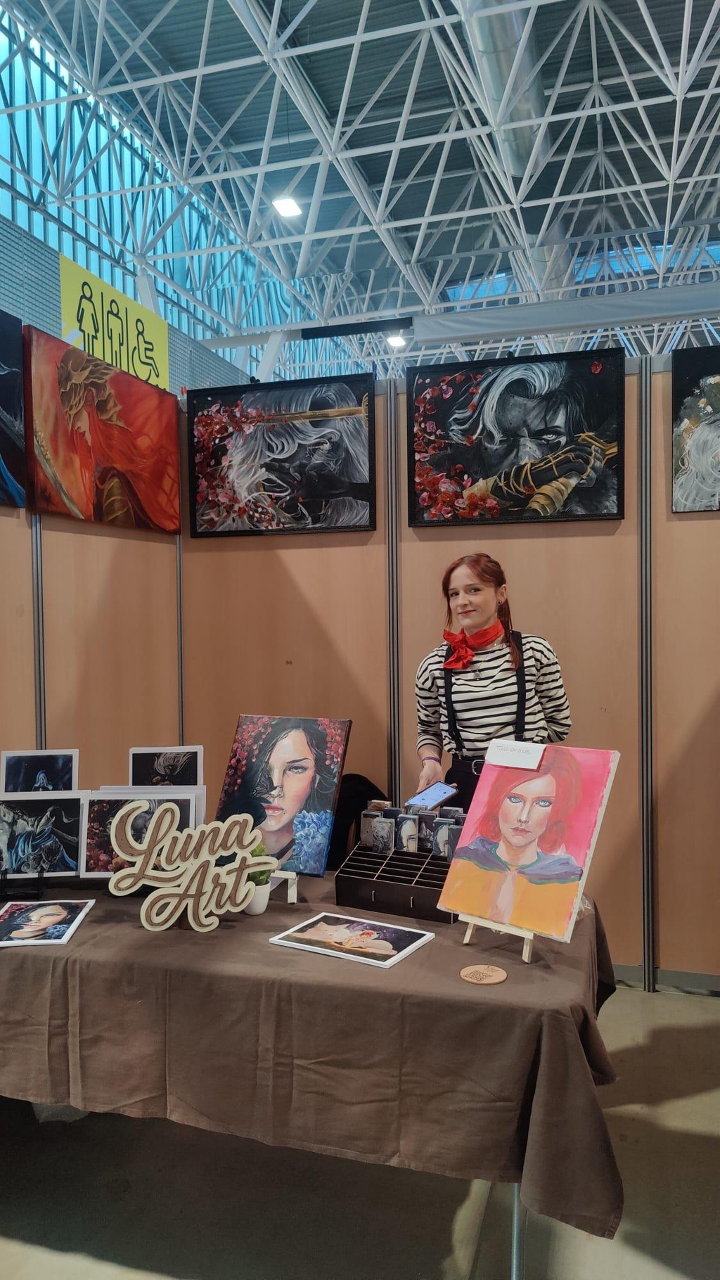 Stand d’artiste avec tableaux originaux et commandes de portraits personnalisés, présentation des toiles créées à la peinture acrylique