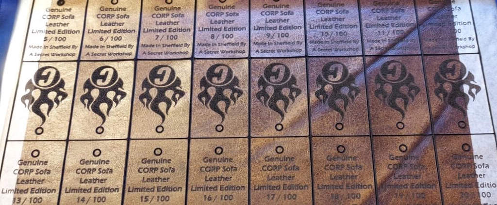 A picture of laser cut CORP keyrings on the laser bed just after cutting
