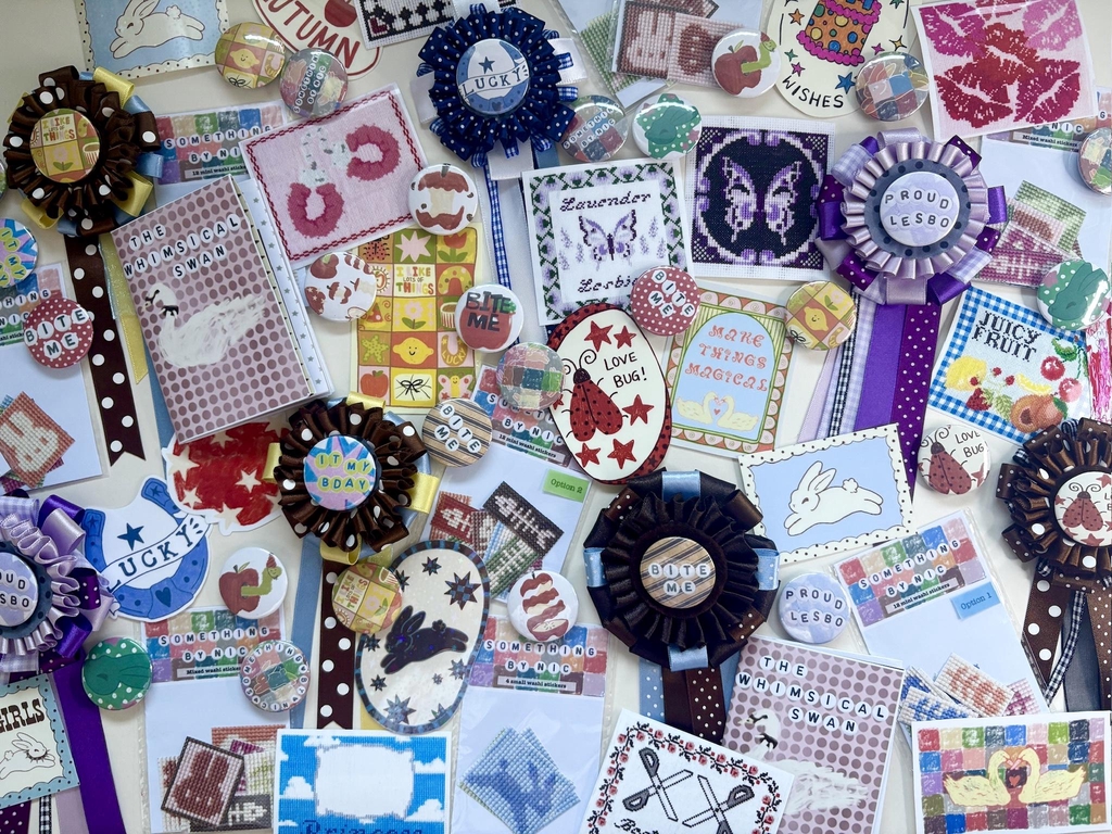 Collection of whimsical products including handmade rosettes, badges, stickers, sticker packs and zines