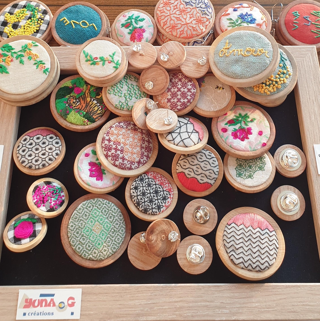 Beaucoup de broches et boucles d'oreilles brodées, en tas sur un cadre.