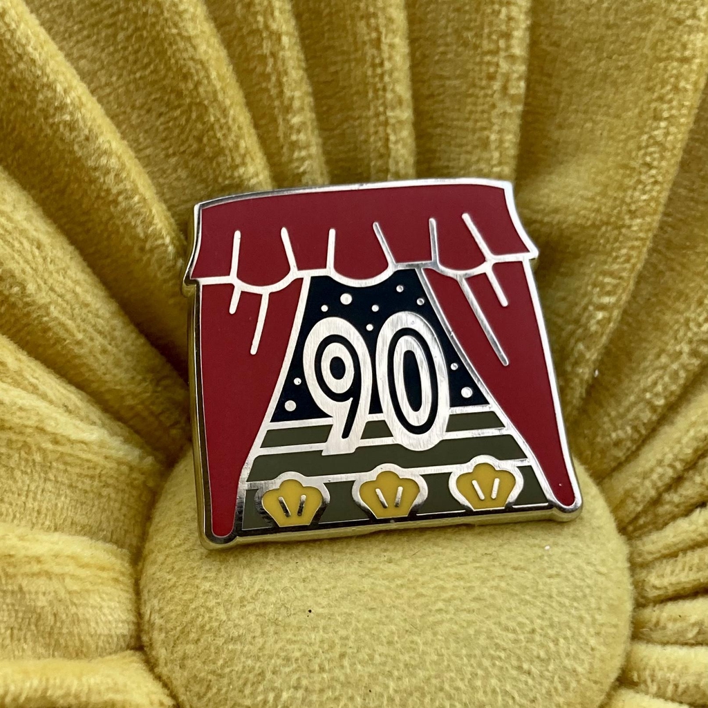 Enamel badge in red black and silver with 90 and theatre curtain design