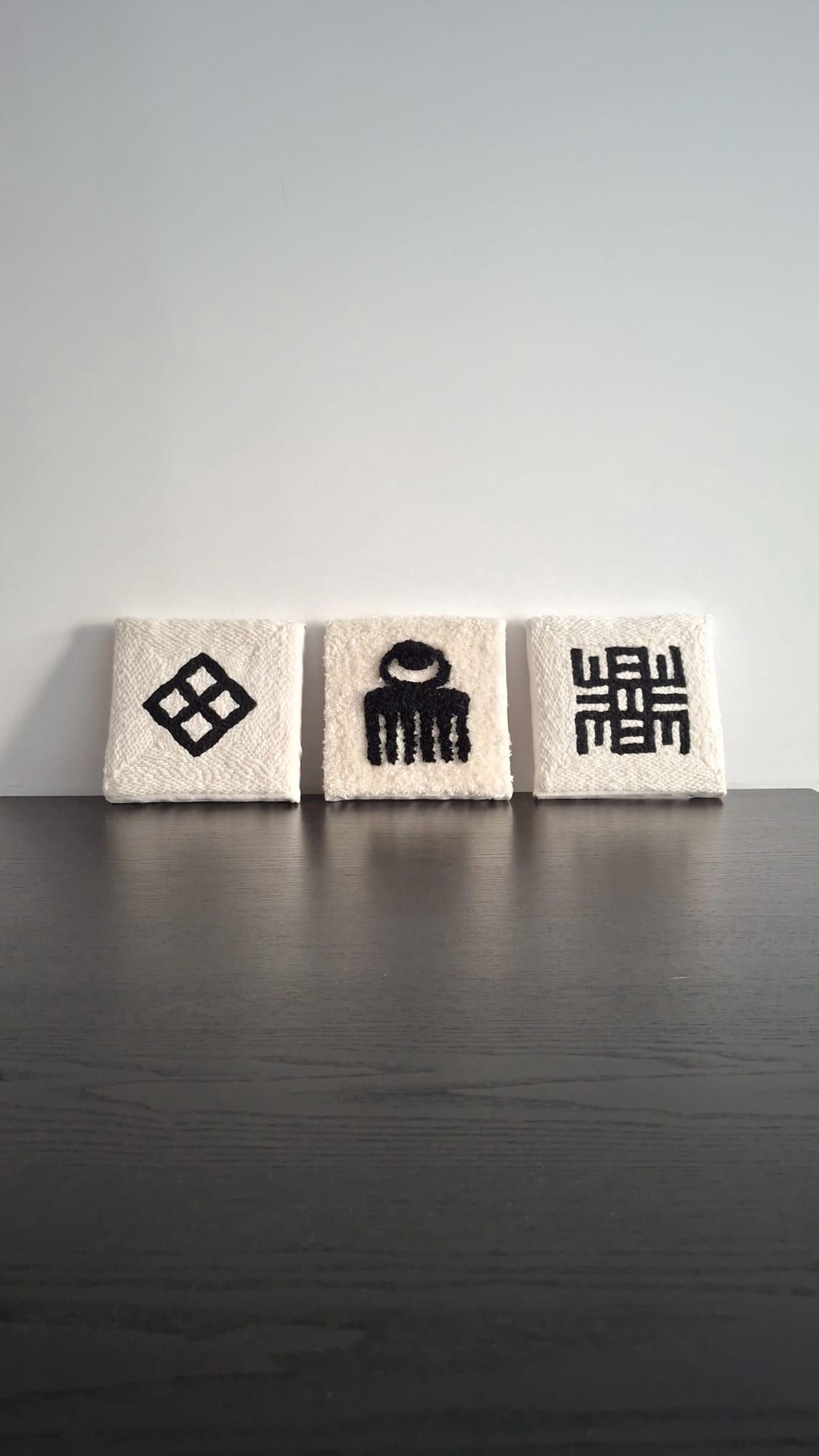 Cadres textiles faits main en punch needle, inspirés des symboles Adinkra d’Afrique de l’Ouest. Pièces murales minimalistes en relief.