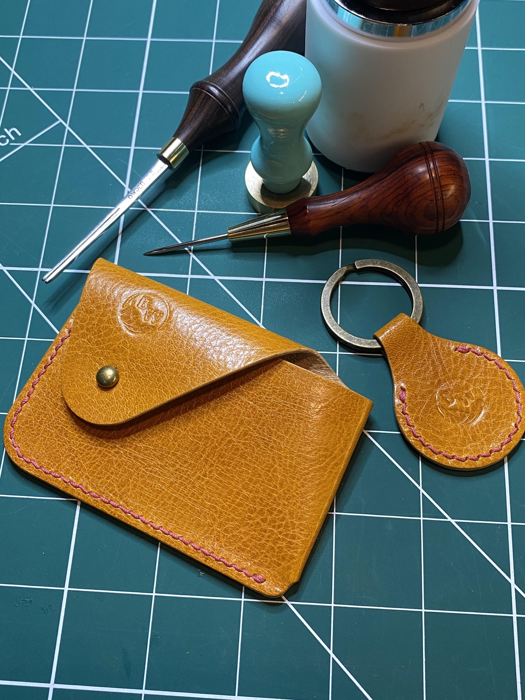 Background photo of honey coloured 'Dalry' card holder and 'Bruntsfield' key fob, both with red contrast stitching and laying on a work bench with leatherwork tools.

Headline reads: "Artisan Leathercraft Handmade in Scotland"

Text reads: "Here at Broken Wing Leathercraft Studio we have a serious passion for making things with our hands, and doing it all the old-fashioned way."

There is a button marked 'Explore' that can be clicked on to access the product range.
