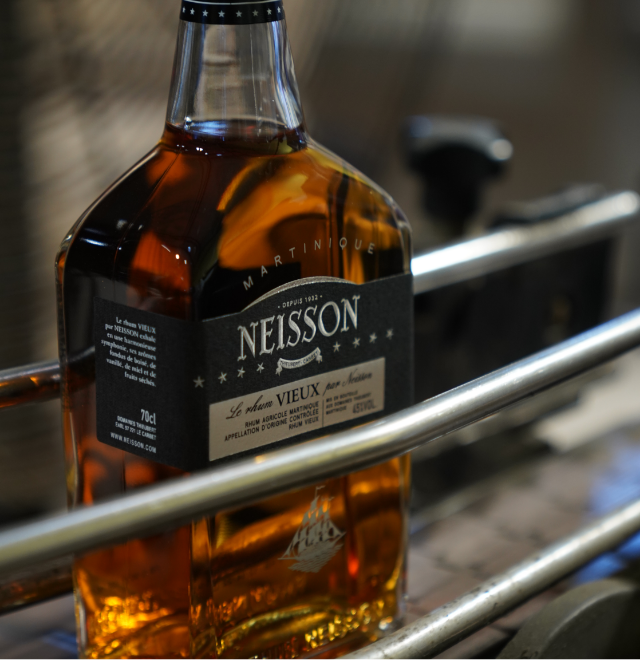 Bouteille de rhum vieux artisanal L'Atelier du 7 posée sur un tonneau en bois