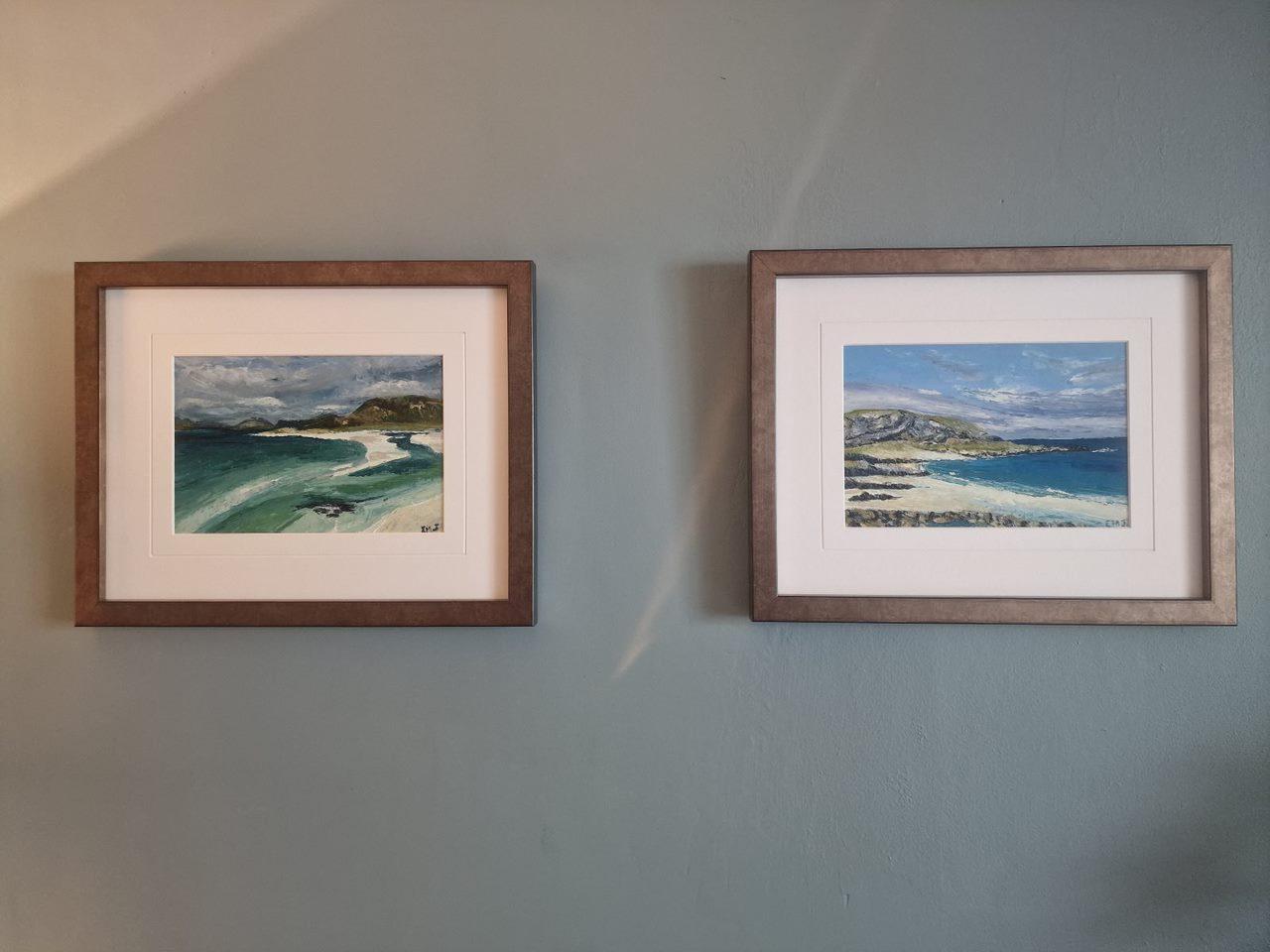 A photo of two oil paintings framed and in their forever home, the paintings are of the Outer Hebrides. Both depict the beautiful white sands and turquoise waters for which the Hebrides are famous for.