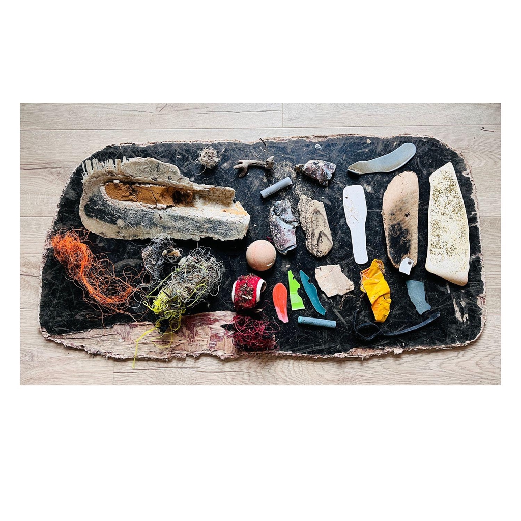 Jane wood - Sculptural assemblage | image shows a selection of plastic and wooden objects collected from beaches in Angelsey on a baclk piece of wood