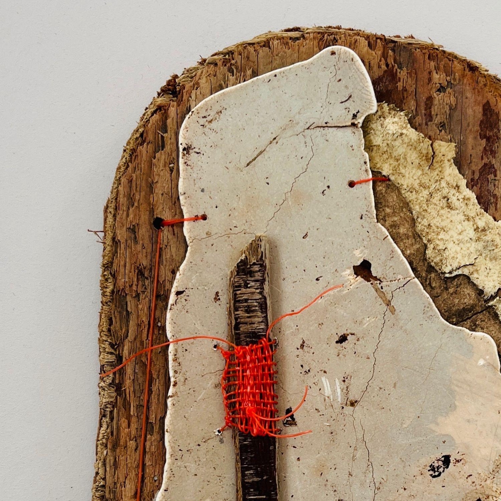 Porth Cwyfan Map | reclaimed wood contemporary textile wall sculpture | Ethical and sustainable art. 
The image shows two artworks made from found objects. One is made from an oval shaped piece of weathered brown wood.  It has plastic, cloth and cardboard attached to it with small sticthes. 