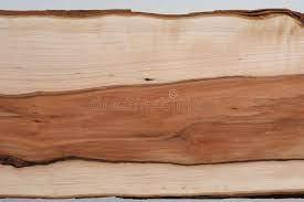 Plan rapproché d'une planche de bois d'aubépine brut révélant un contraste marqué entre l'aubier clair et le cœur de bois brun orangé au veinage fluide.
