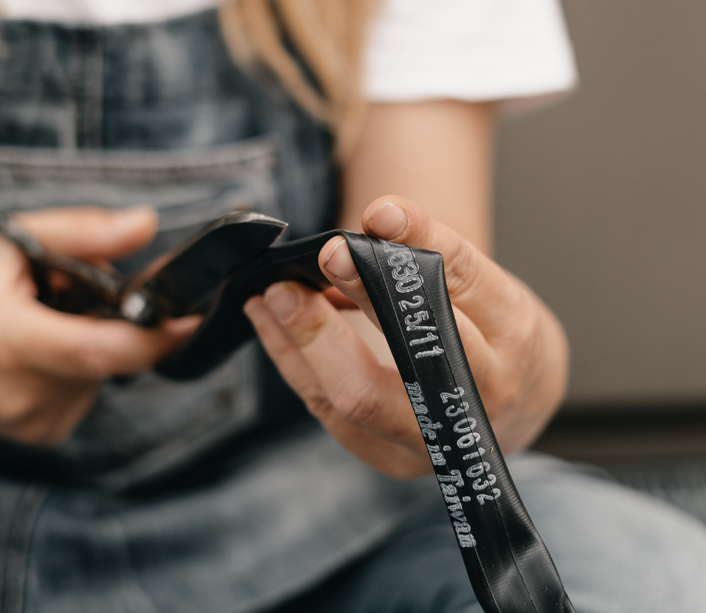 Mãos a cortar uma camara de ar de bicicleta