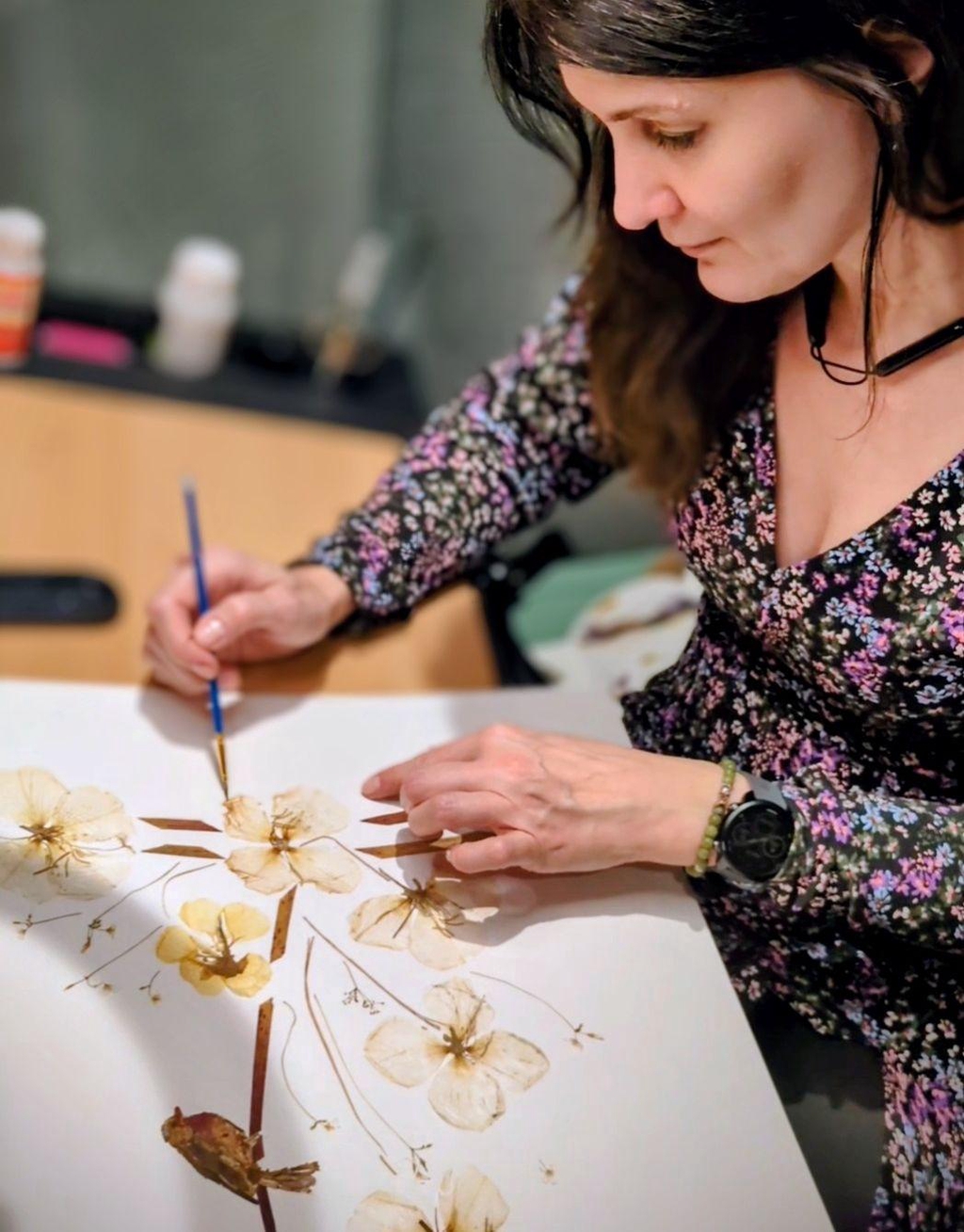 Artiste Herbier Art travaillant des fleurs séchées pour créer un tableau unique inspiré de la nature