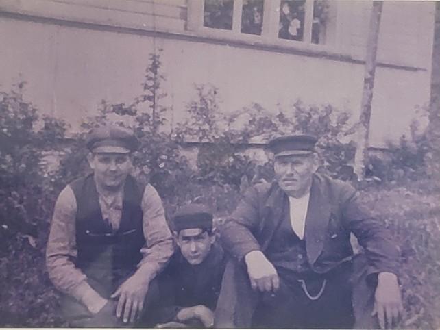 Tilan karjamestari, isäntä ja hänen poikansa istumassa talon edessä 1900-luvulla.