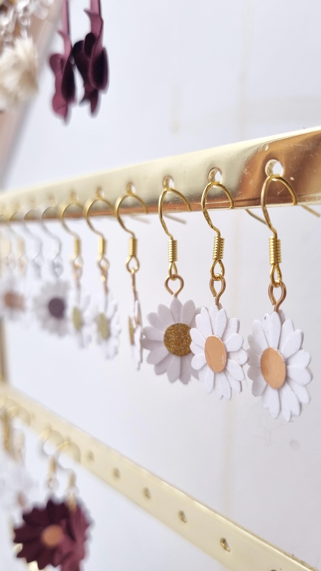 un tres gros zoom sur des boucles d'oreilles présentées sur un presentoir fond blanc