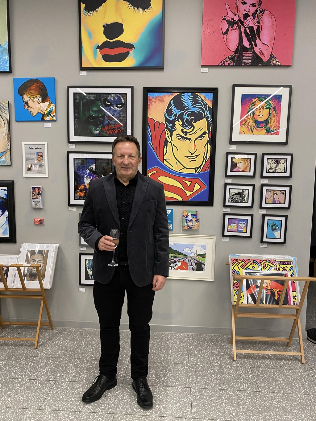 Image of artist Nigel Matthews standing in front of some of his artwork at an art exhibition.