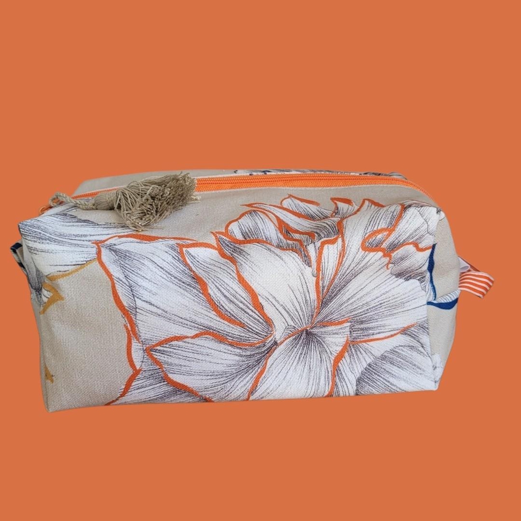 Trousse de toilette rectangulaire en tissu en bleu, orange, roses et ocre sur fond crème