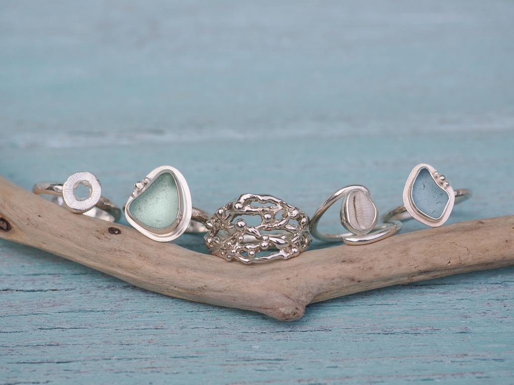Selection of sea glass, cowrie and silver rings.
