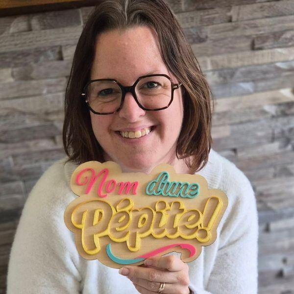 Émilie, créatrice de Nom d'une Pépite, présentant une pancarte de porte artisanale en mixed media