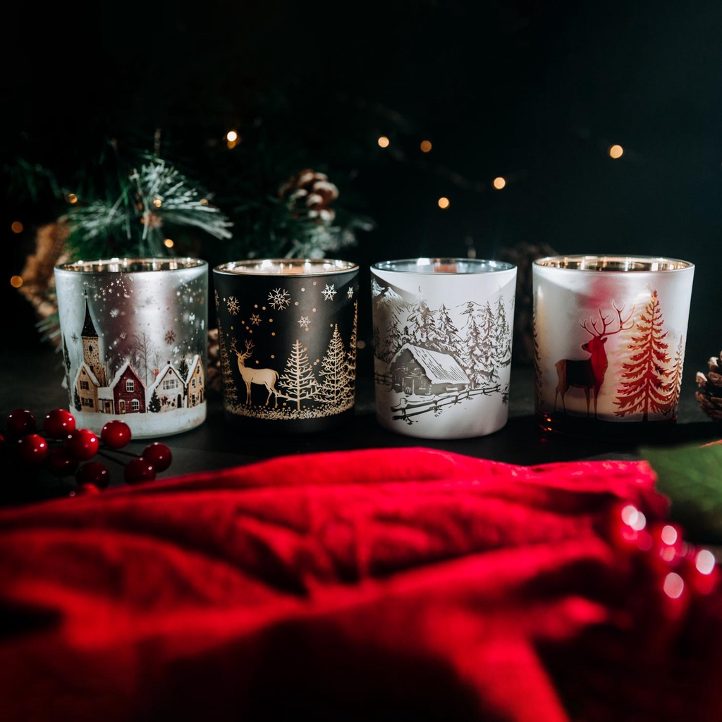 Colección de Navidad en recipientes con doble pintado, dejando entre ver la luz de la vela en sus dibujos.
