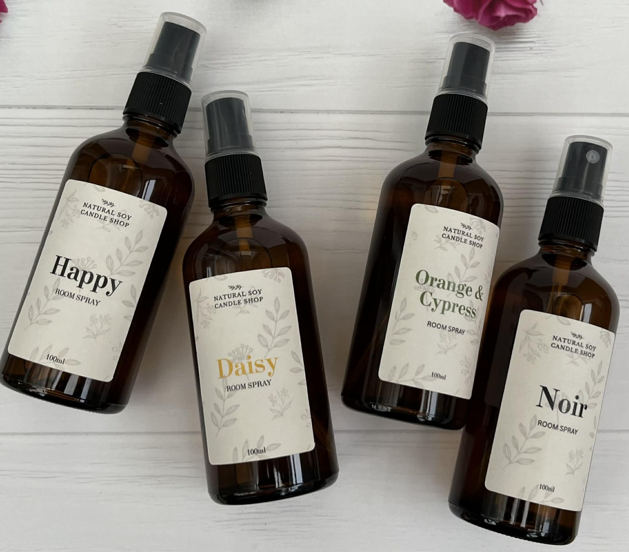Four amber glass spray bottles filled with fragrance, they have natural soy candle shop on the labels.