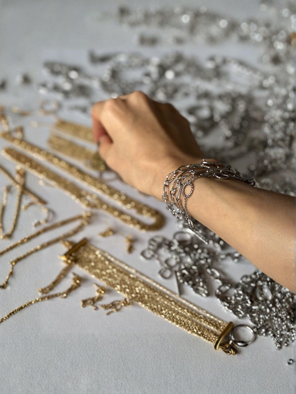 Main avec bracelets Joyae en acier inoxydable en accumulation, attrapant un bijou parmi les créations faites main pour femmes et hommes.