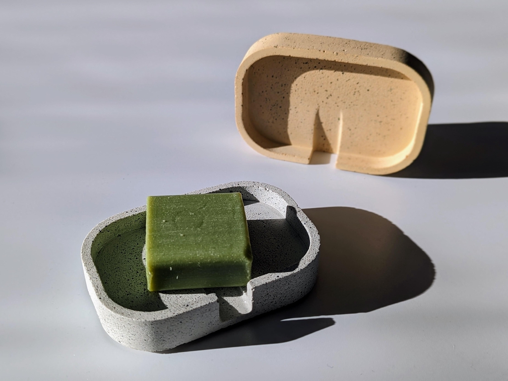 Two soap dishes, one white, one yellow with a green soap bar on it