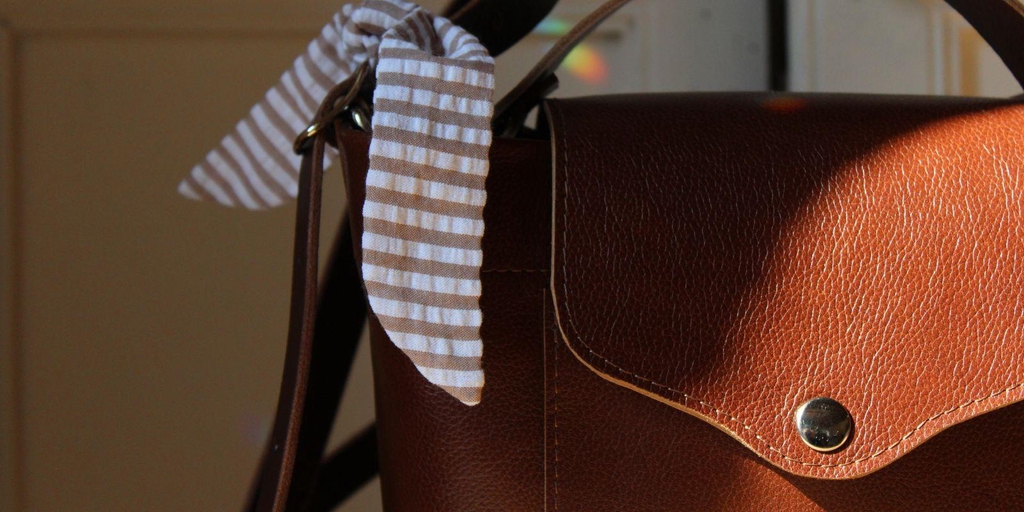 Détail du sac bandoulière en cuir marron pour femme avec ruban rayé, modèle 31mai.